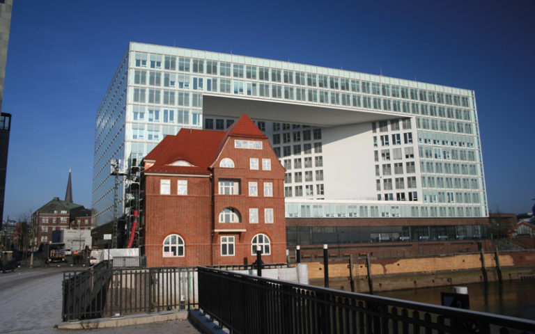 (Dach-)Sanierung des denkmalgeschützten „Alten Zollamtes“ HafenCity Hamburg Sanierter Backsteinbau vor moderner Architektur.